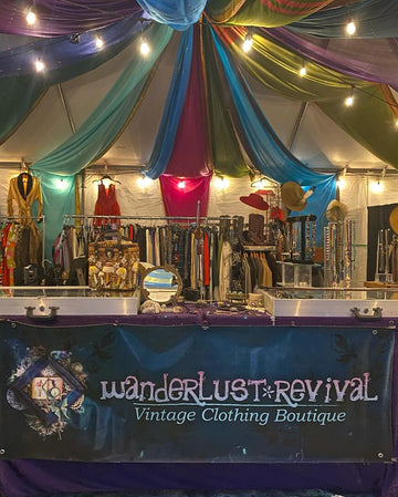 Vintage clothing boutique with colorful drapes and a 'wanderlust revival' sign.