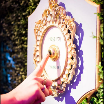 Decorative door with 'Press for Champagne' button, hand pressing it, outdoor setting