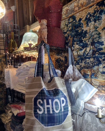 Tote bag with 'SHOP' printed on it hanging in a store setting.