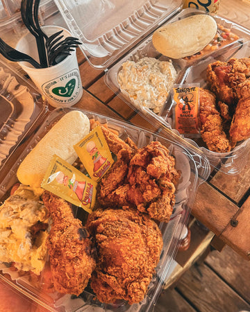 Plated fried chicken with sides and drinks on a wooden table