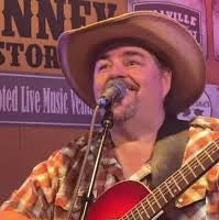 Person playing guitar and singing into a microphone at a live music venue.