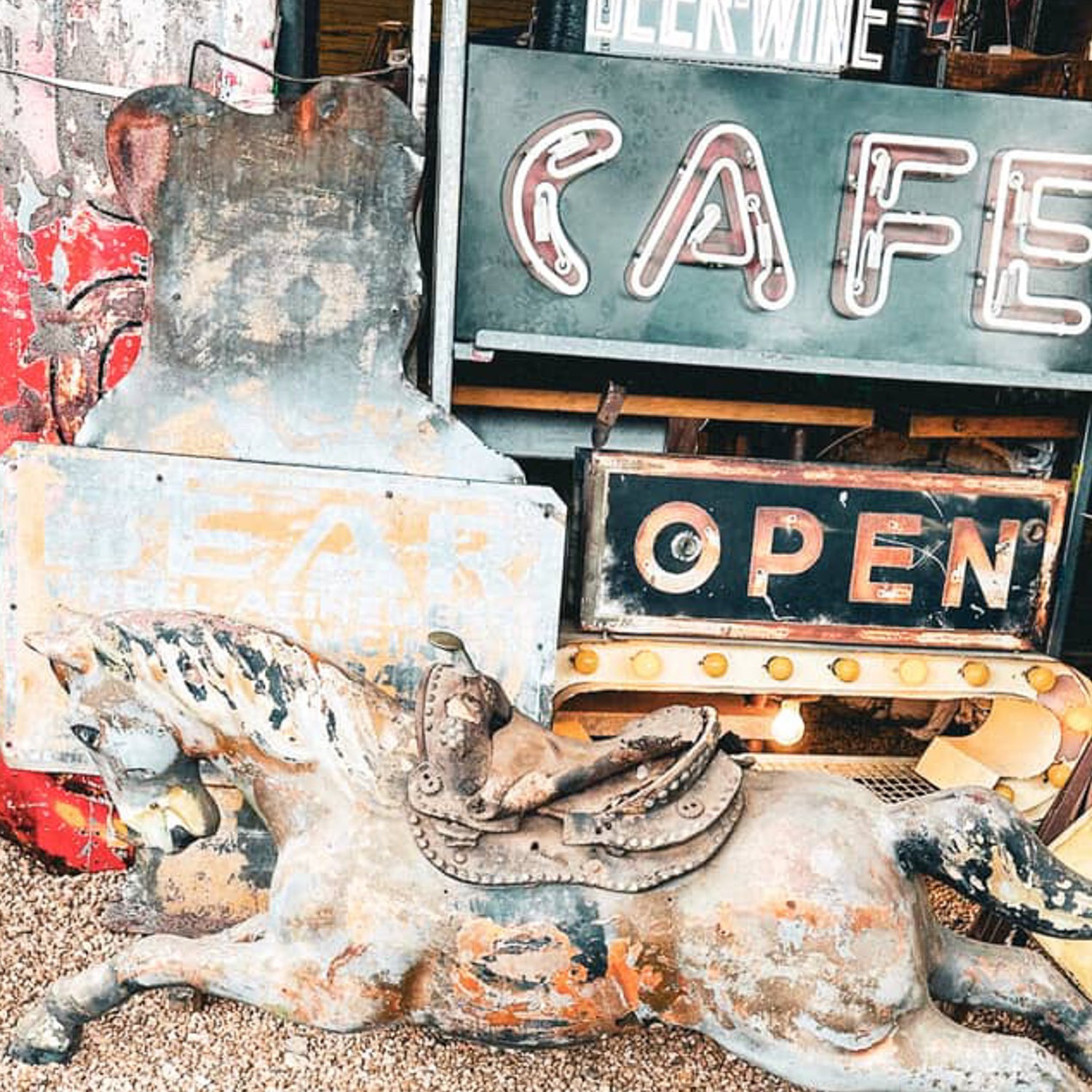 Rustic metal cow sculpture with vintage signs in the background