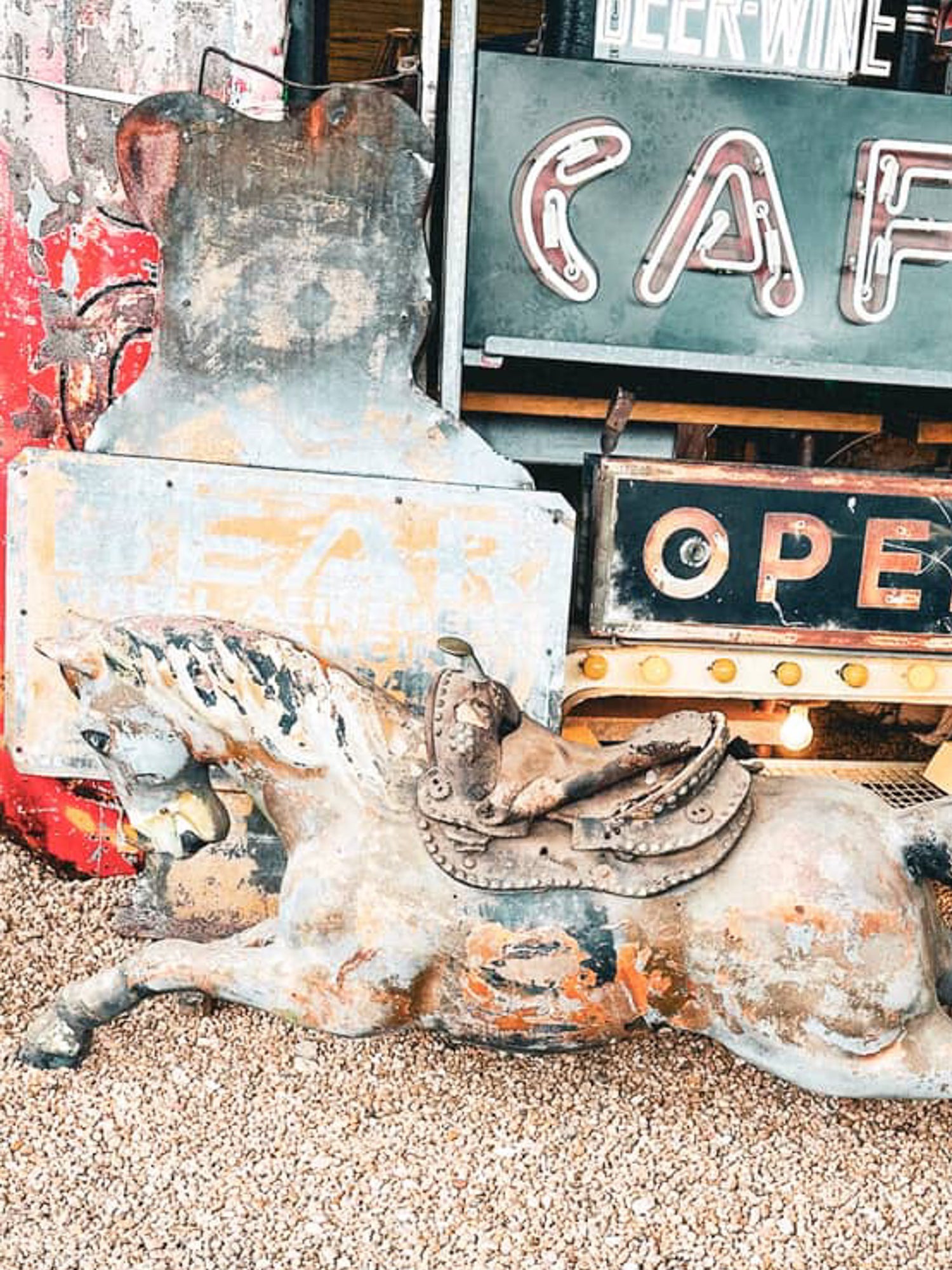 Rustic metal cow sculpture with vintage signs in the background