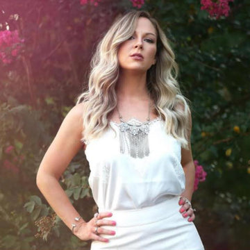 Woman in a white dress standing in front of a floral background