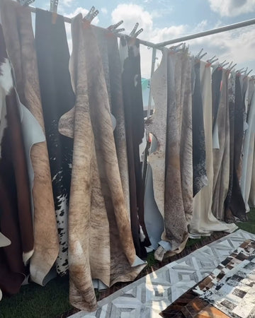 Textiles hanging on a clothesline with a patterned rug and outdoor setting.