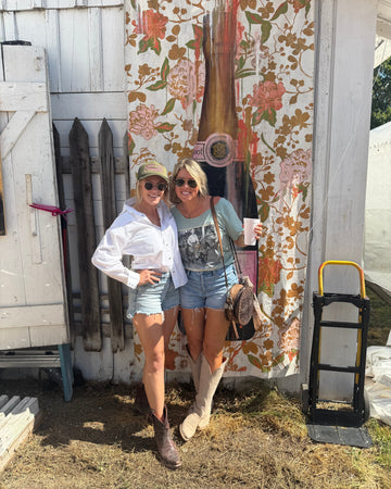 Two people taking a selfie in front of a floral-patterned wall at Zapp Hall in Round Top Texas