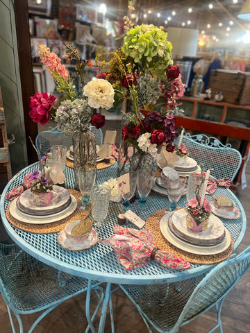 Decorative table setting with flowers and tableware on a metal table.