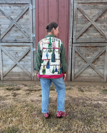 Person wearing a colorful jacket standing in front of wooden barn doors.