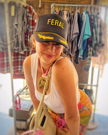 Person wearing a cap with 'FERAL' text in a clothing store.