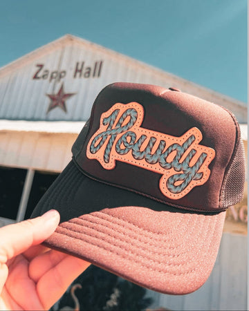 Cap with 'Howdy' text held in front of a building with 'Zapp Hall' signage.