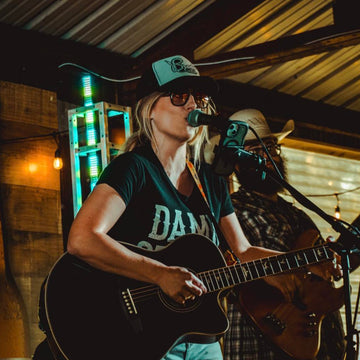 Person playing guitar and singing into a microphone in a casual setting