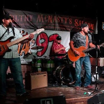 Two musicians playing guitars on a stage with a banner in the background