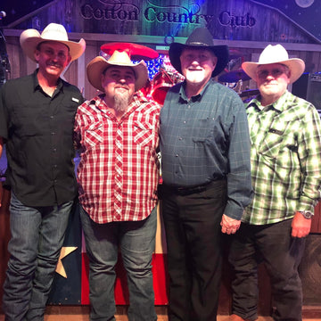 Four men in cowboy hats posing together in front of a Cotton Country Club sign.