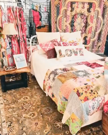 Bed with floral bedding and pillows in a store setting with colorful decor.