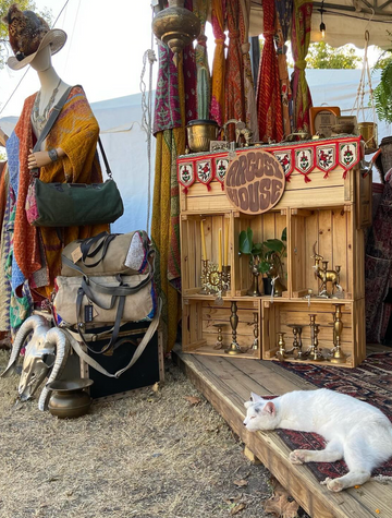 Vintage-style wooden booth with decorative items and a cat lying on a step.