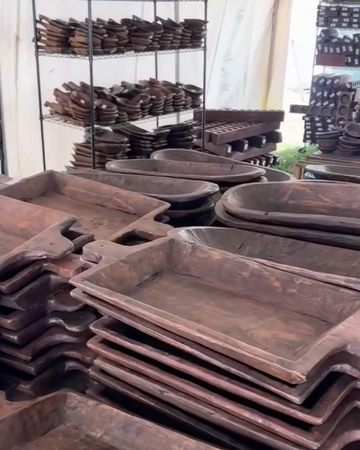 Stacks of metal trays in a warehouse setting with shelves in the background.