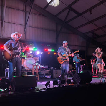 Band performing on stage with musical instruments under colorful lights.