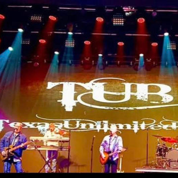 Band performing on stage with 'Texas Unlimited' logo projected onto the floor.