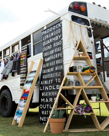 White bus with wooden display stands and decorative items outdoors