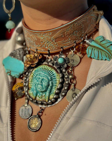 Close-up of a person wearing a decorative belt with tribal-themed jewelry, including turquoise stones and metal pendants.